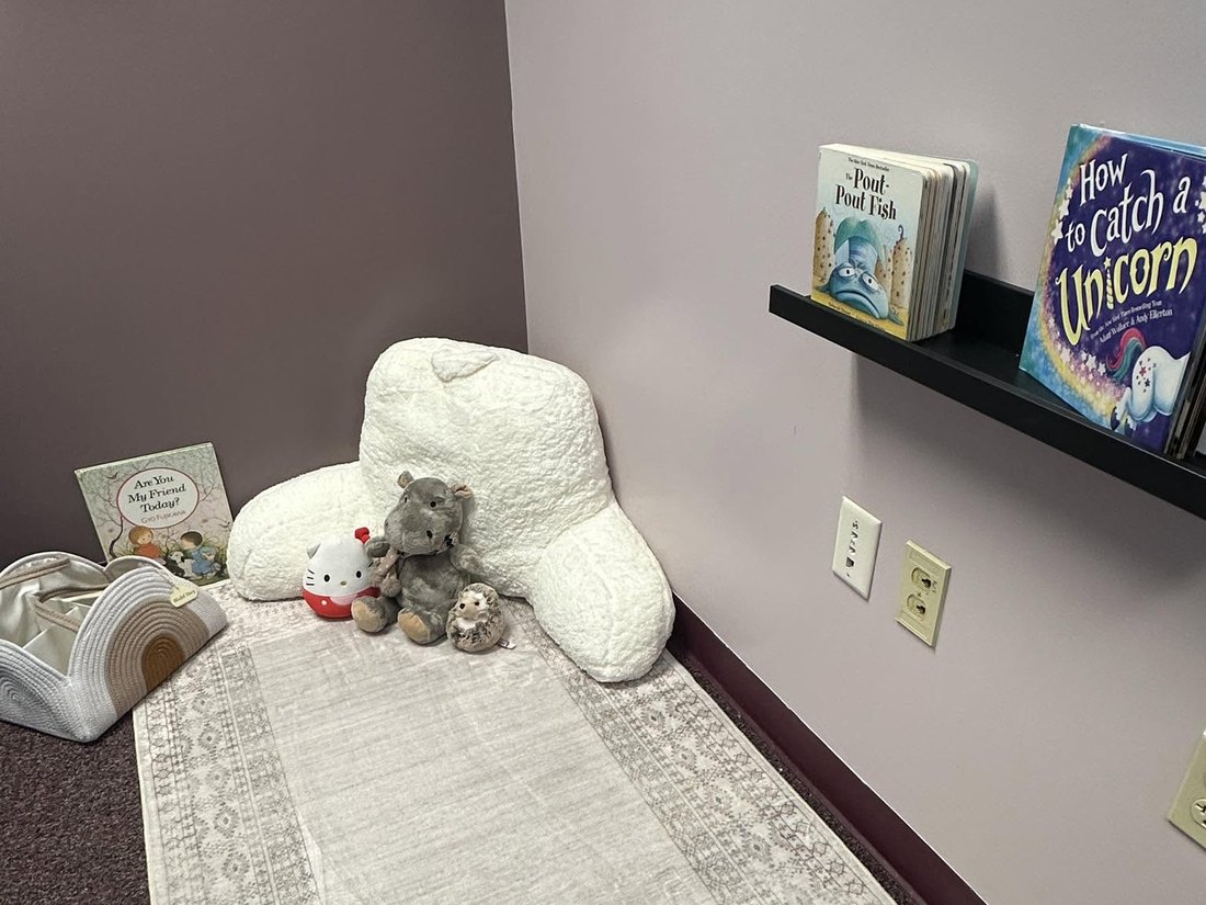 The reading corner at CoreLogic Learning with a soft rug, pillow, stuffed animals, and a picture-book ledge